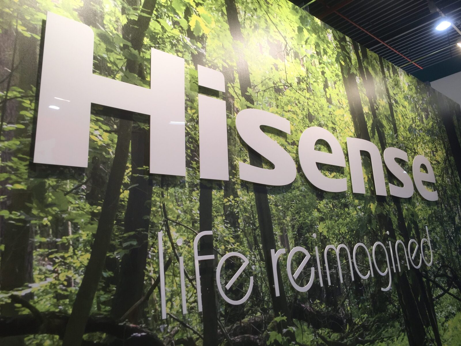 Merkwand van de Hisense-beursstand met logo op een bosprint