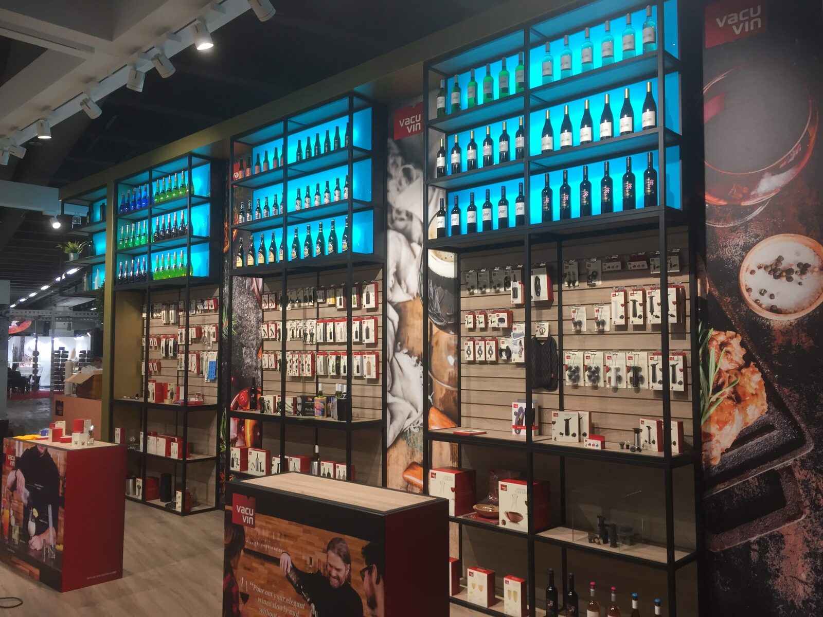 Beursstand van Vacu Vin met blauw verlichte schappen vol flessen en producten