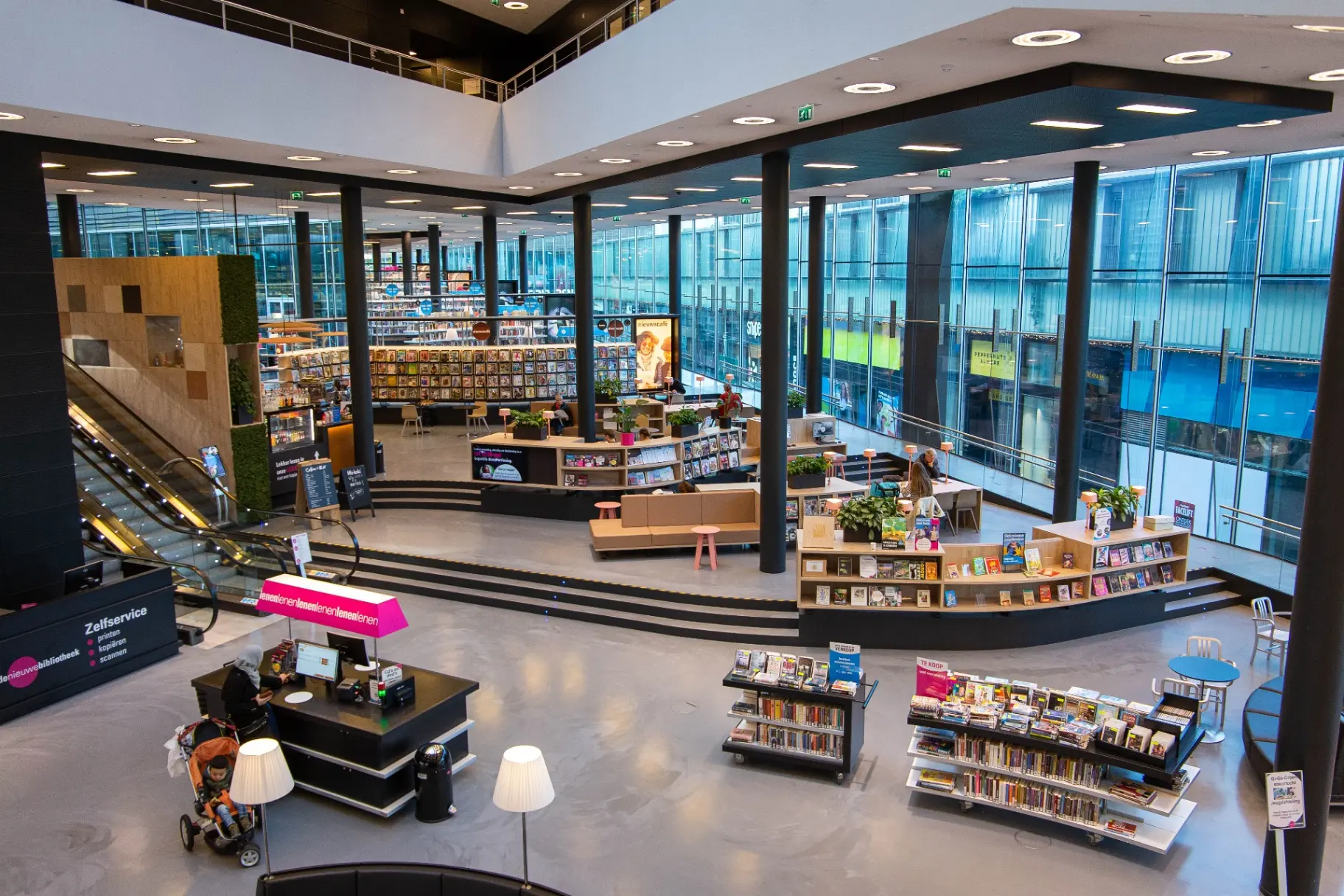 Ruime bibliotheekvloer met balies, presentatiemeubels en zitplekken